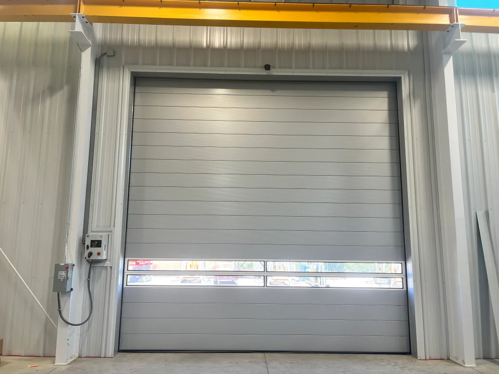 Interior view of a fully closed grey industrial bay door with a window section, illustrating When to Replace Your Sectional Overhead Door.