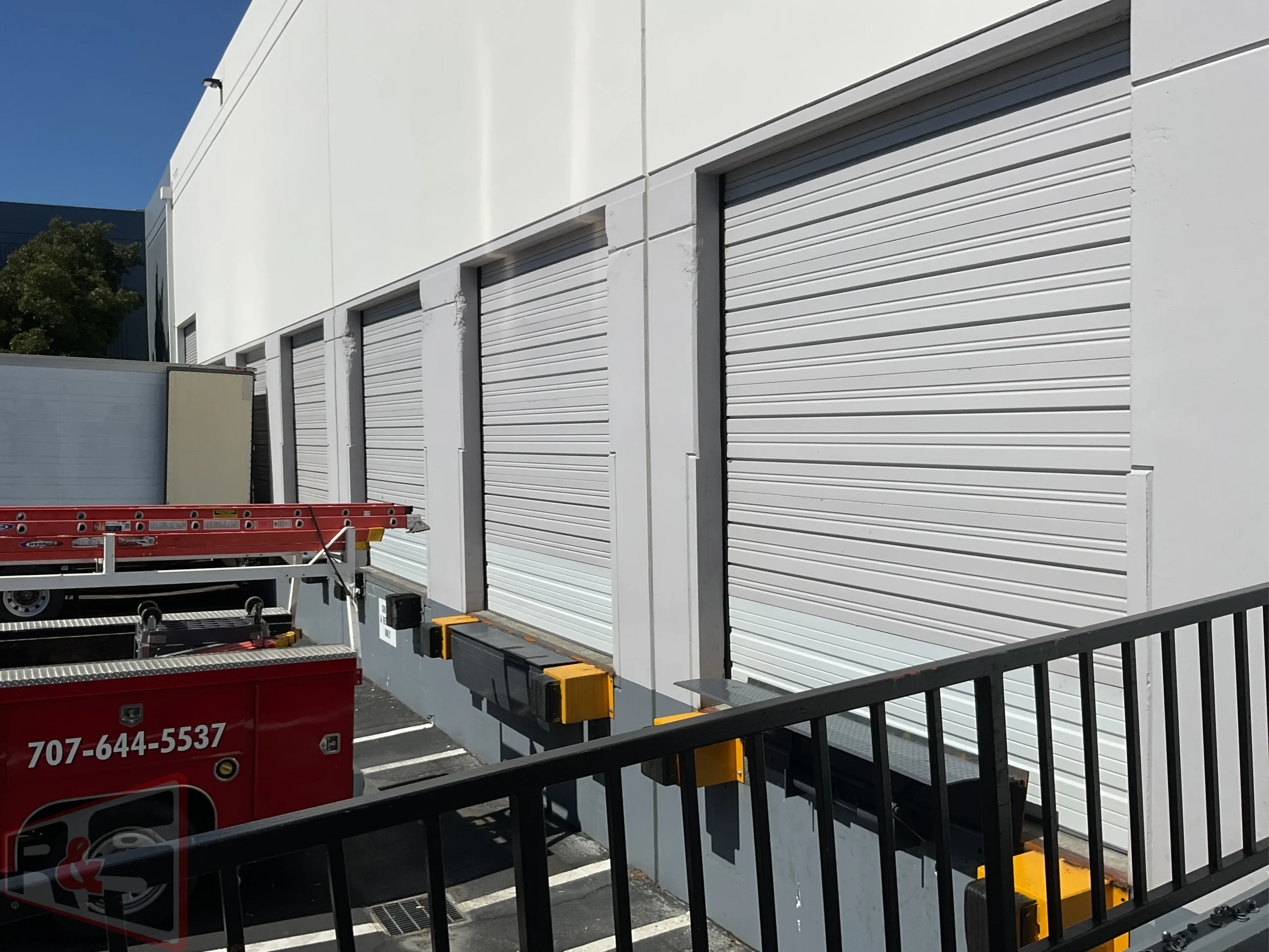 A row of industrial bay doors equipped with dock bumpers and safety guards for loading dock equipment in Vallejo.