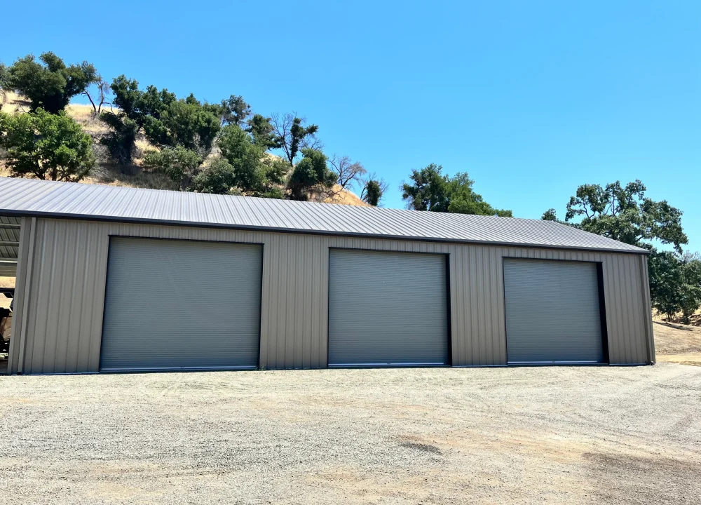 Three large grey metal roll-up Commercial Garage Doors installed on a modern industrial warehouse building.