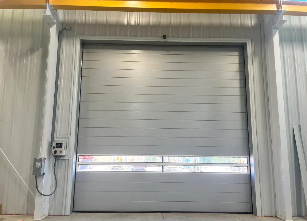 Interior view of a fully closed grey industrial bay door with a window section, illustrating When to Replace Your Sectional Overhead Door.